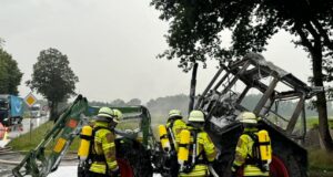 Einsatzkräfte der Feuerwehr vor dem ausgebrannten Traktor in Luhdorf. Foto: Hamann